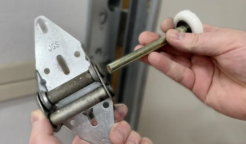 Worn garage door hinge and new nylon roller